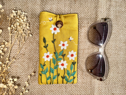 Yellow embroidered linen glasses case with white daisies and bee accents, padded to protect glasses from scratches and damage.