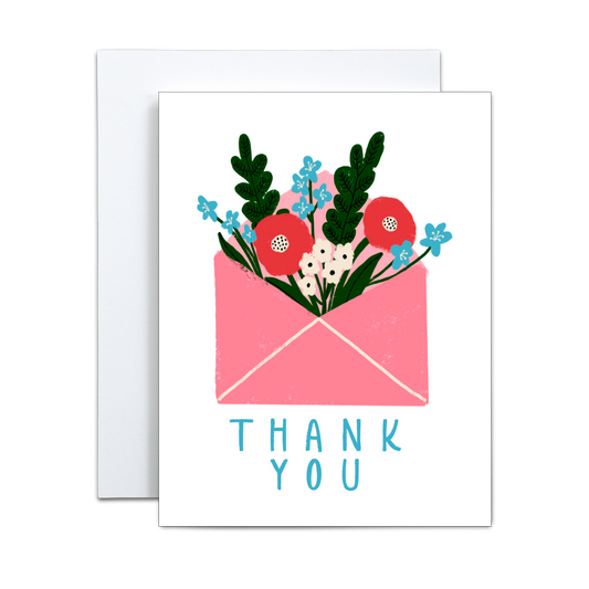 The Copper & Print Handmade Thank You Greeting Card features a pink envelope with colorful flowers and green leaves, "THANK YOU" in blue capitals below, and comes with an additional blank card partially visible behind.