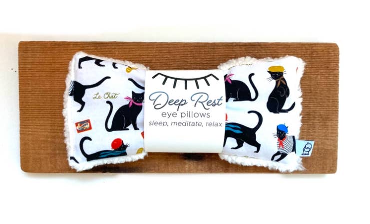 Deep Rest Eye Pillow with black cat design displayed on a wooden surface, crafted for stress relief and enhancing meditation sessions.