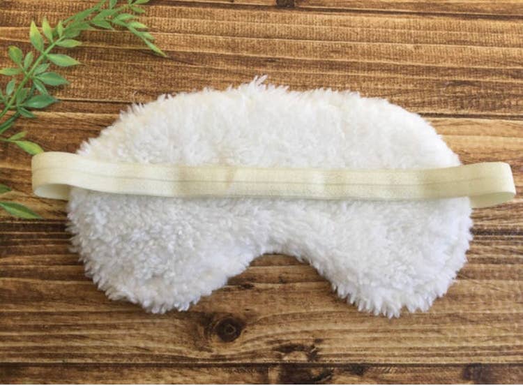 White fluffy sleep mask on wooden surface