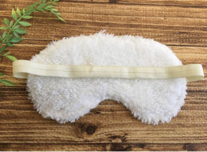 White fluffy sleep mask on wooden surface