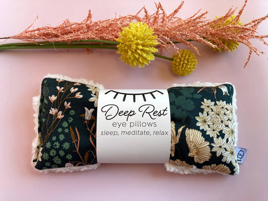 Emerald Weighted Eye Pillow shown with decorative flowers, designed for stress relief, acupressure, and calming meditation sessions.