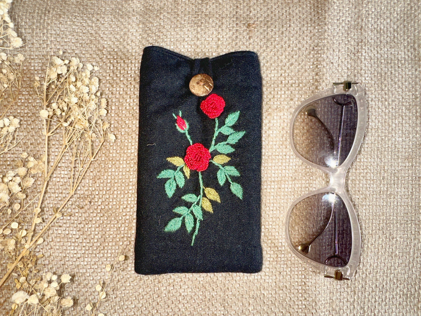 Black linen glasses case with red rose embroidery and wooden button, combining elegant design with padded eyewear protection.