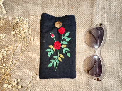 Black linen glasses case with red rose embroidery and wooden button, combining elegant design with padded eyewear protection.