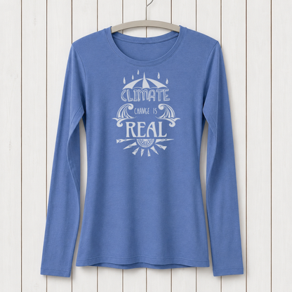 Blue long sleeve T-shirt with white graphic design featuring an umbrella, water waves, and the message 'Climate Change is Real' on a white wooden background
