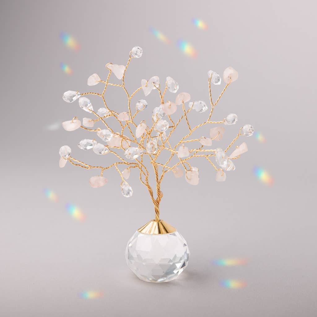 Rose Quartz Suncatcher Tree of Life with crystal and stone branches on a faceted glass base, casting rainbow reflections in soft lighting.
