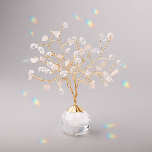 Rose Quartz Suncatcher Tree of Life with crystal and stone branches on a faceted glass base, casting rainbow reflections in soft lighting.