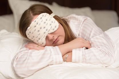 Woman sleeping with Wink Sweet Dreams Cotton Sleep Mask, showcasing comfort and fit for a peaceful night’s rest in cozy home setting.