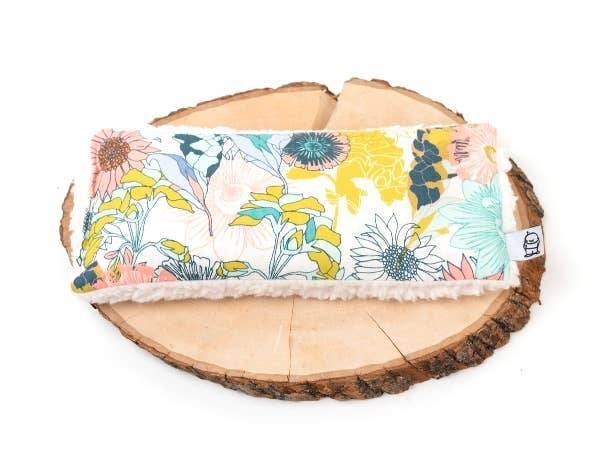 Floral Meadow Deep Rest Eye Pillow on wooden base, weighted for relaxation and ideal for cooling or heating therapy.