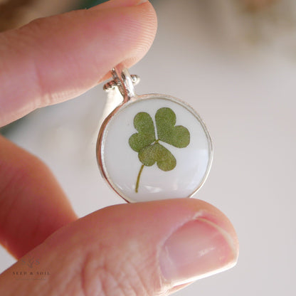 Hand holding a round silver clover pendant necklace with real clover. A meaningful gift for St. Patrick’s Day or everyday wear.