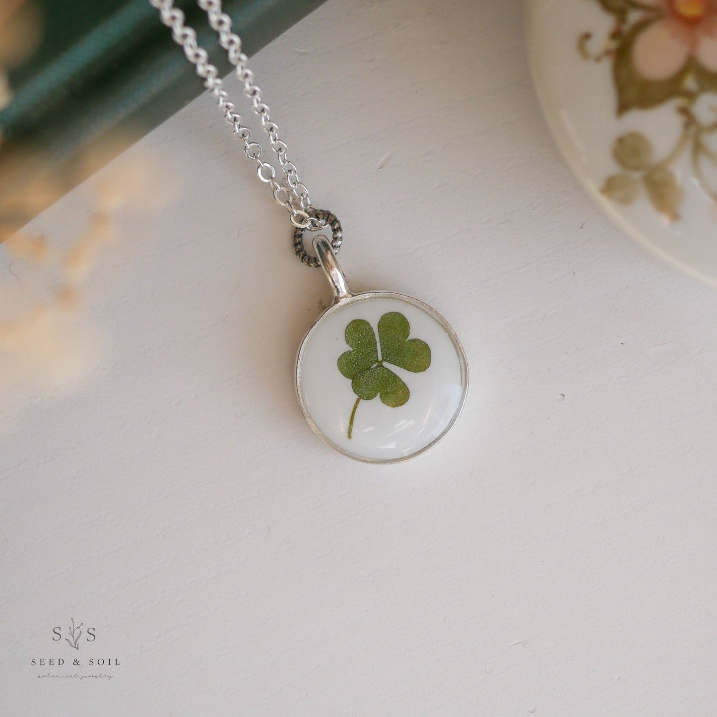 Round silver clover necklace with real clover encased in resin. Delicate and symbolic jewelry for luck and love.