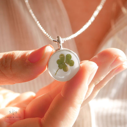 Round clover pendant necklace in silver held in hand, highlighting real clover detail. Perfect for celebrating St. Patrick’s Day.