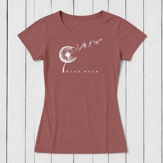 Rust-colored women's graphic T-shirt made of bamboo and organic cotton featuring a white dandelion seed head with flying seeds and the phrase 'wish more' below, casual style