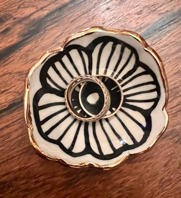 3" handmade flower-shaped jewelry dish with 22K gold accents holding two rings, showcasing its use for elegant jewelry storage.