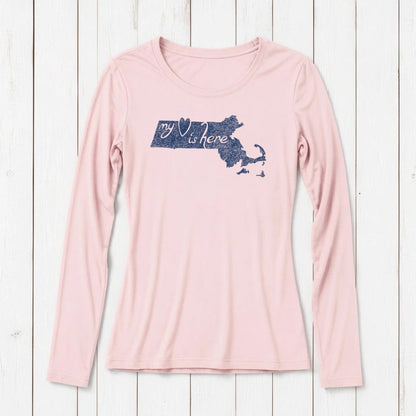 Light pink women's long sleeve T-shirt with navy blue Massachusetts map graphic and text 'my heart is here' on a white wooden background