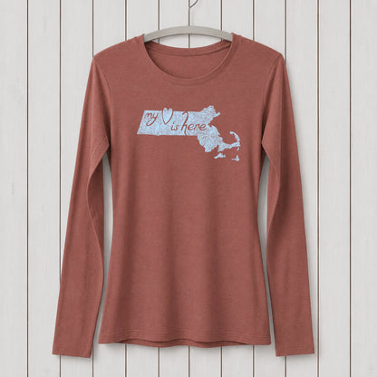 Rust-colored women's long sleeve T-shirt made of organic cotton and bamboo blend with a Massachusetts map and 'my heart is here' graphic design, hanging on a white wooden wall.