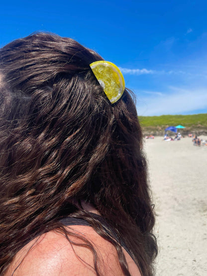 Sunshine Yellow Lemon Claw Hair Clip worn in wavy hair at the beach, perfect for summer styling and secure hold in outdoor settings.