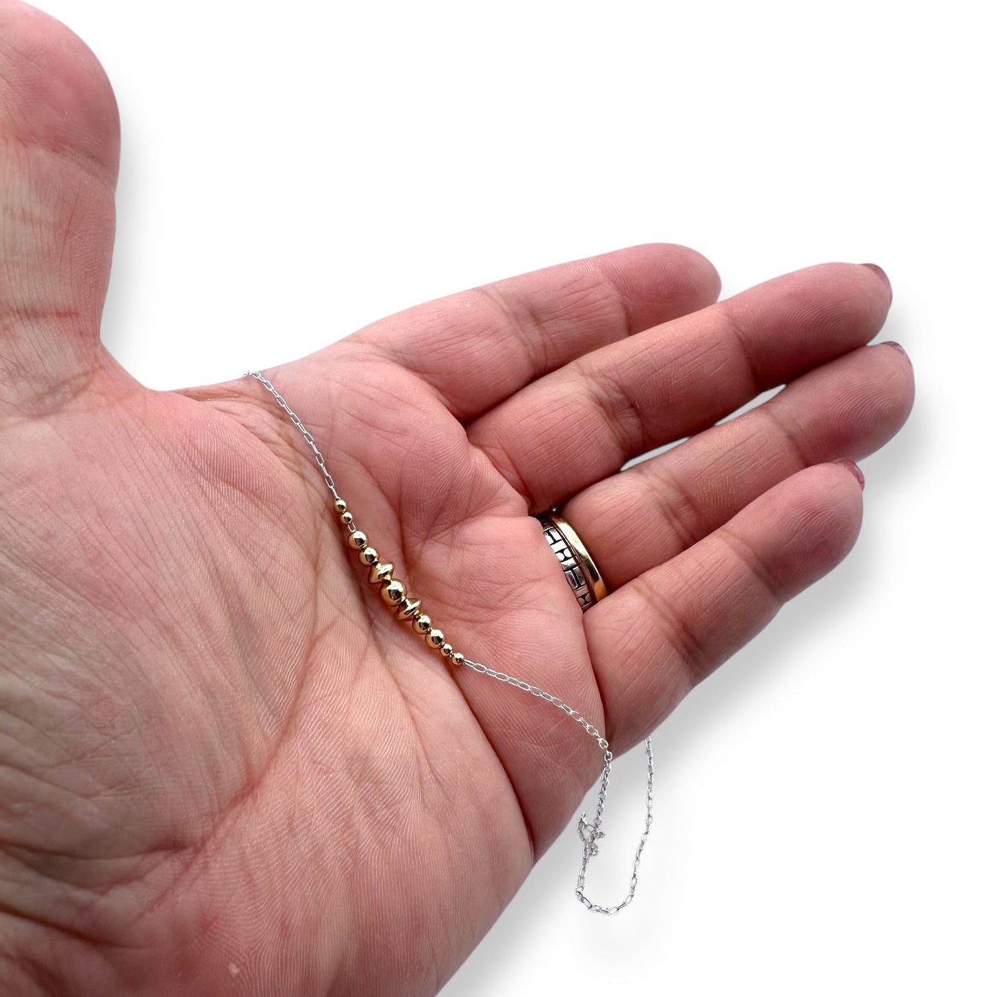 Hand holding silver and gold bead necklace