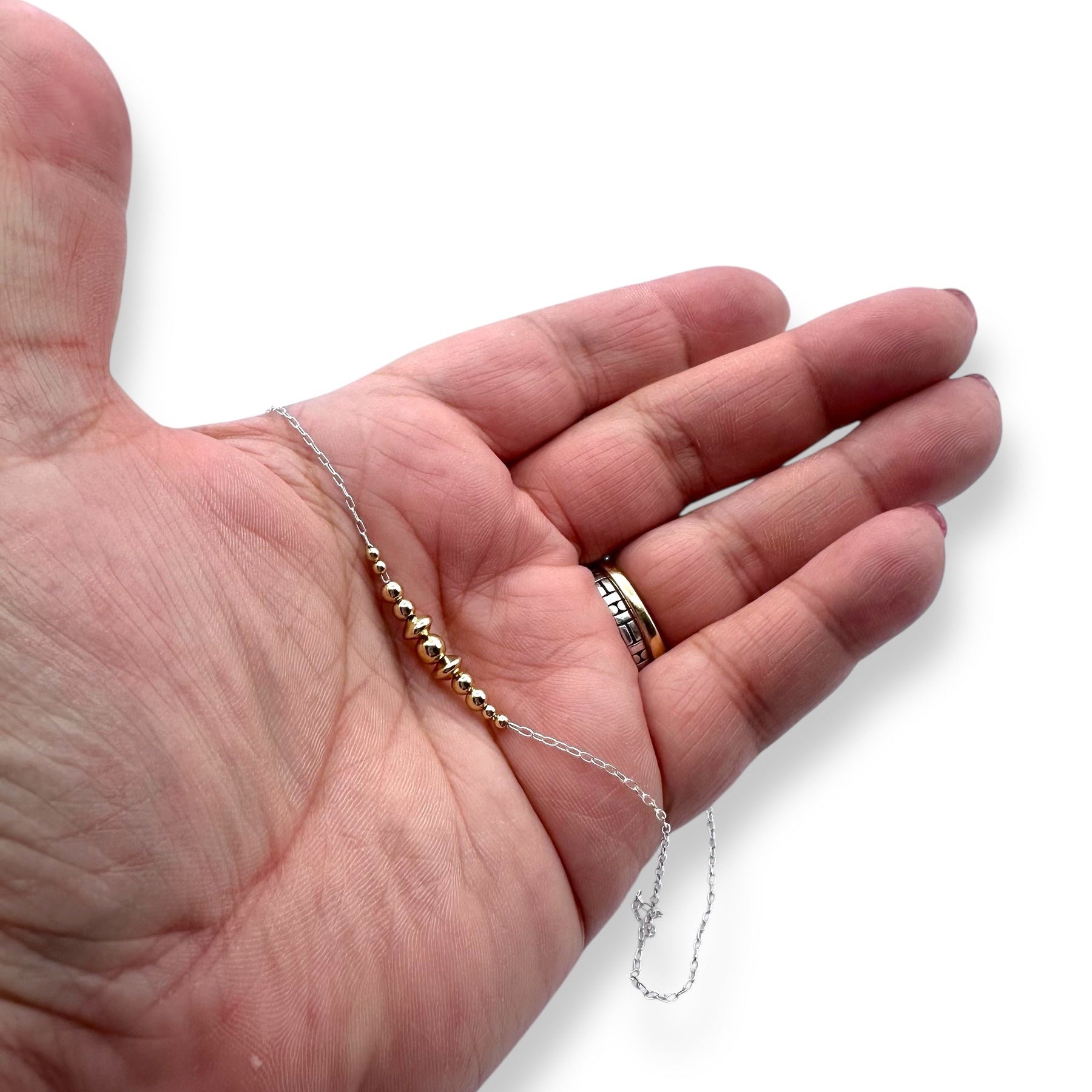 Hand holding silver and gold bead necklace