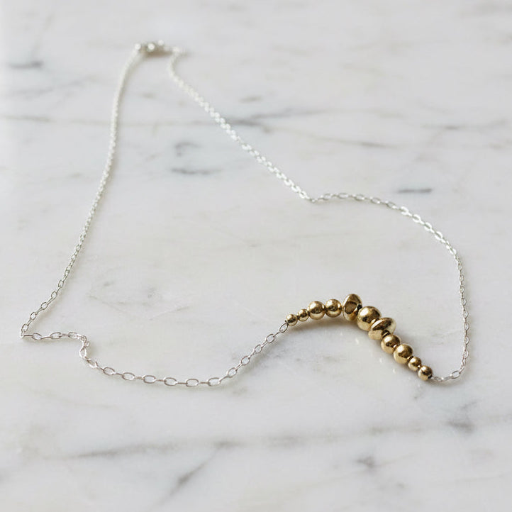Silver and gold bead necklace on white background