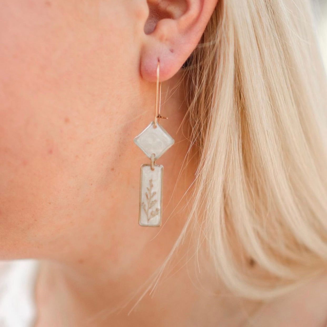 Midas Art Deco Dangle Earrings worn on ear, showing elegant 2.5-inch drop length and shimmering opalescent background with fern detail.