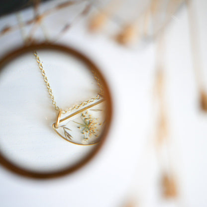 Artistic view of Meadow Luna Necklace through magnifying glass, emphasizing intricate botanical details in resin pendant.