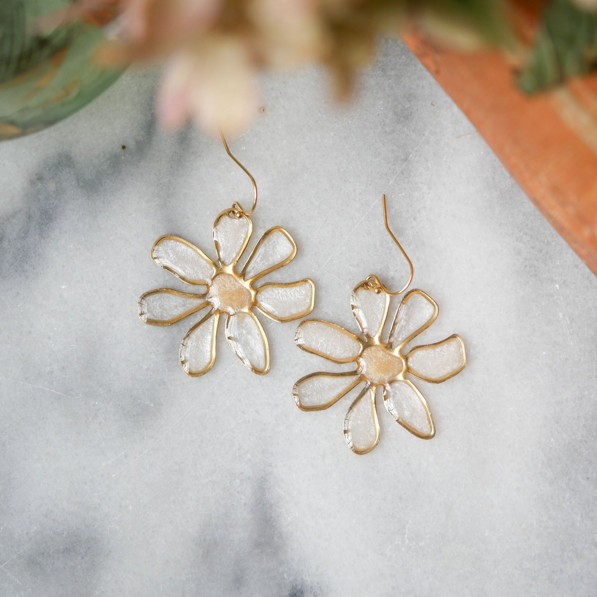 Close-up of peach-centered daisy stained glass earrings with gold trim. Lightweight summer accessory, available at Seed&SoilShop.
