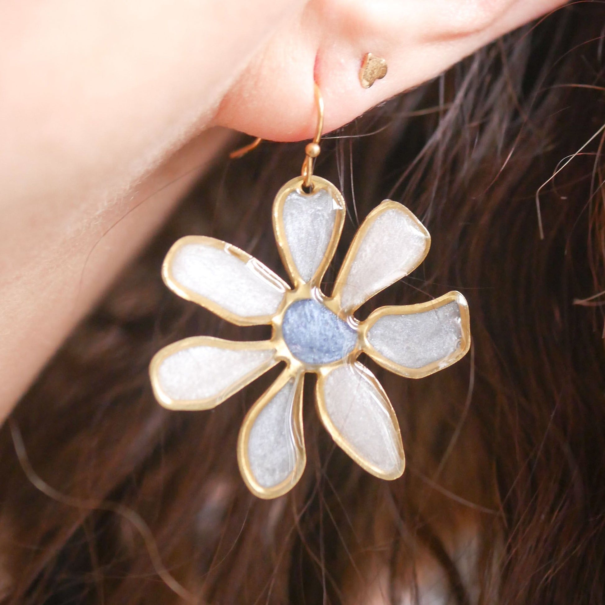 Model wearing blue-centered daisy stained glass earring, showcasing lightweight floral design. Summer-ready jewelry, shop now.