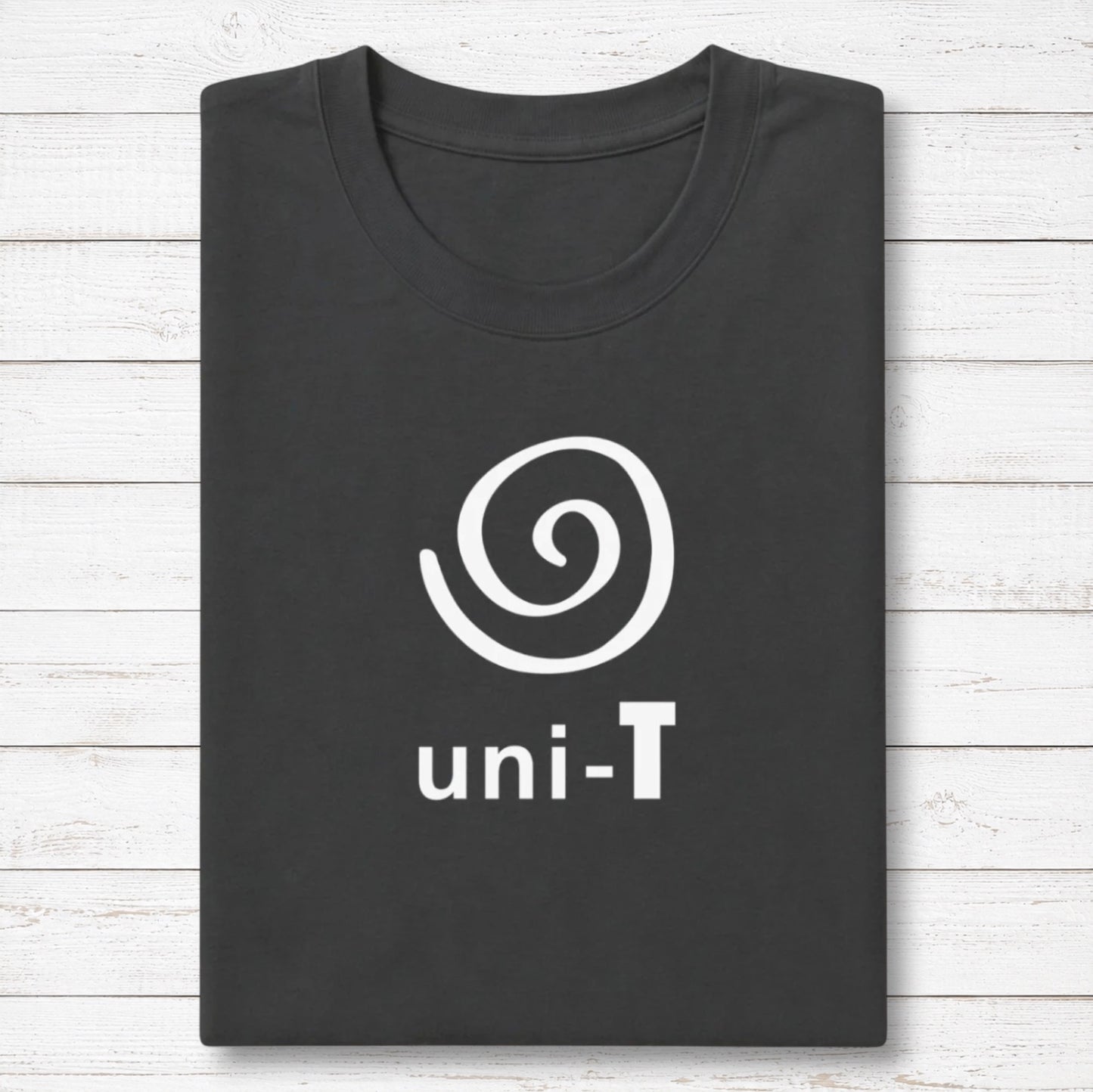 Uni-T black bamboo and organic cotton t-shirt with a white spiral unity graphic, neatly folded on a white wood surface.