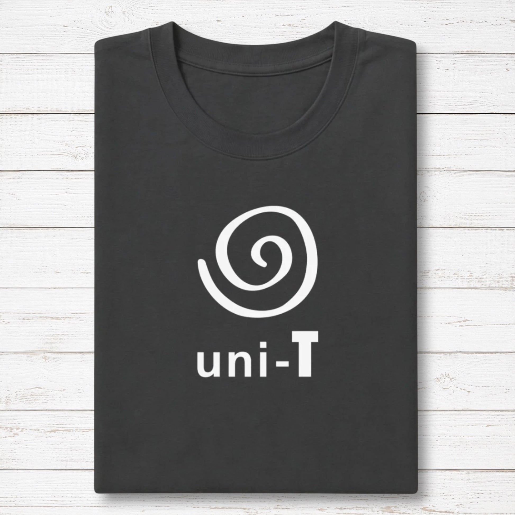 Uni-T black bamboo and organic cotton t-shirt with a white spiral unity graphic, neatly folded on a white wood surface.