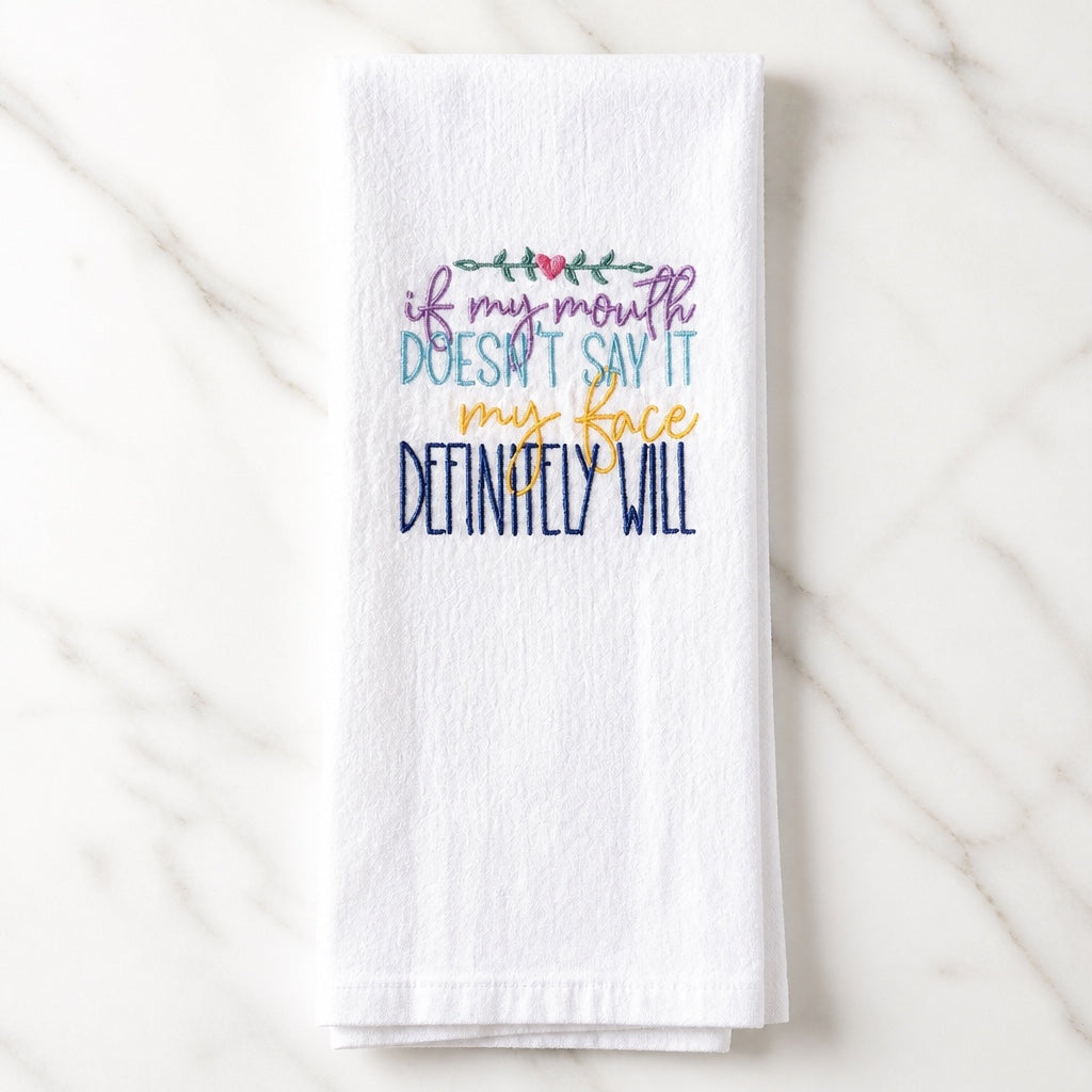 Uni-T white flour sack towel with colorful embroidered text about facial expressions and a small heart detail