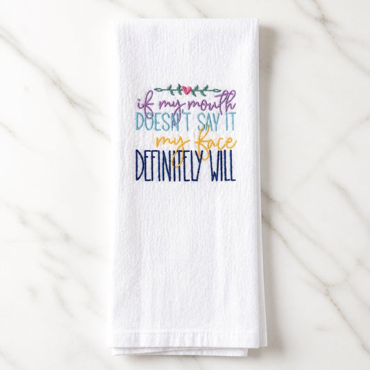 Uni-T white flour sack towel with colorful embroidered text about facial expressions and a small heart detail