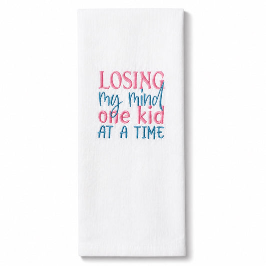 Uni-T white flour sack kitchen towel with pink and blue embroidered text reading Losing my mind one kid at a time