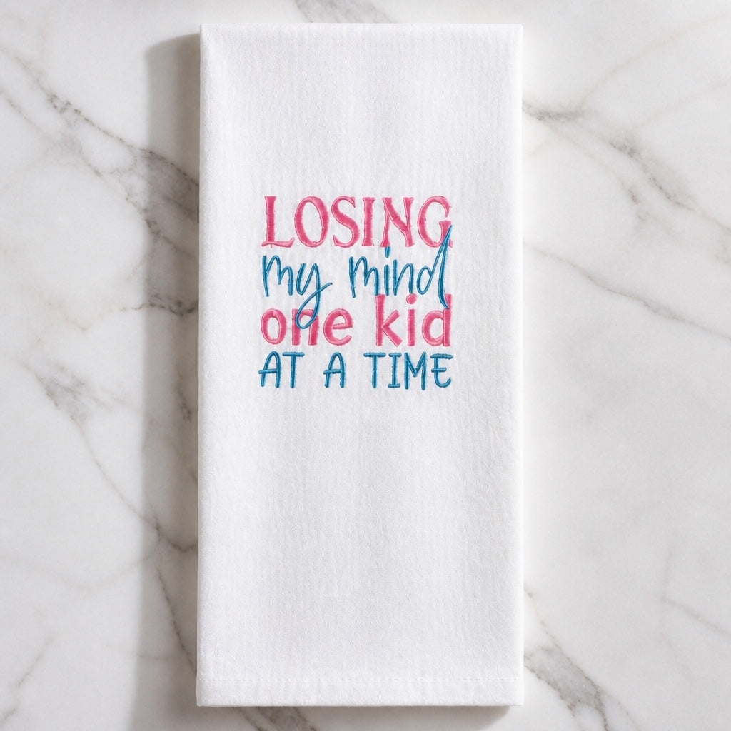 Uni-T white flour sack kitchen towel with pink and blue embroidered text reading Losing my mind one kid at a time