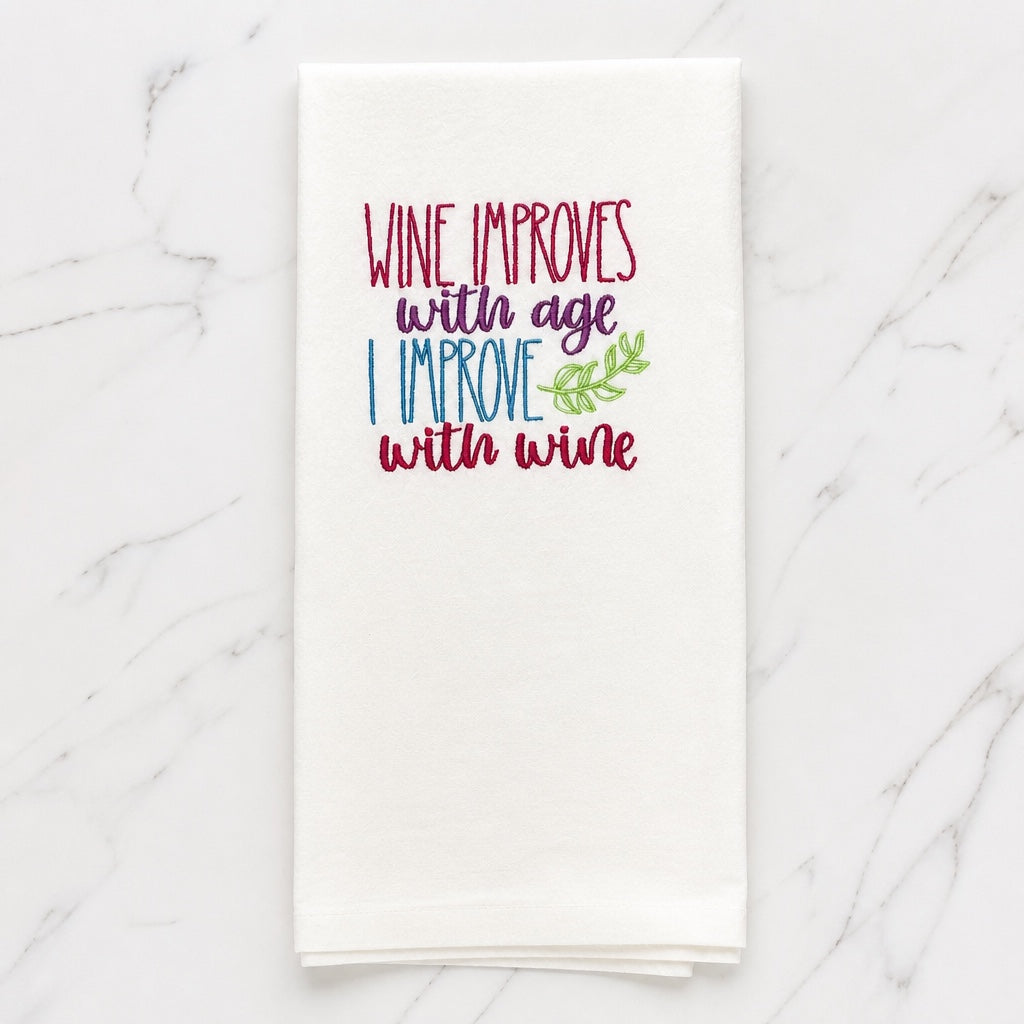 Uni-T white flour sack towel with colorful embroidered text Wine improves with age I improve with wine