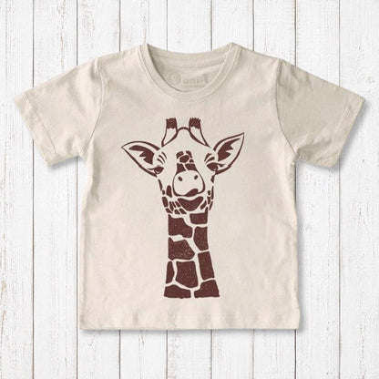 Uni-T organic cotton kids t-shirt in cream with a brown whimsical giraffe illustration on a white wooden background