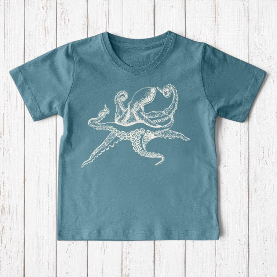Uni-T kids organic cotton t-shirt in blue with a white hand-illustrated octopus graphic on a rustic wood background.