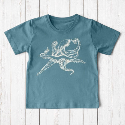 Uni-T kids organic cotton t-shirt in blue with a white hand-illustrated octopus graphic on a rustic wood background.