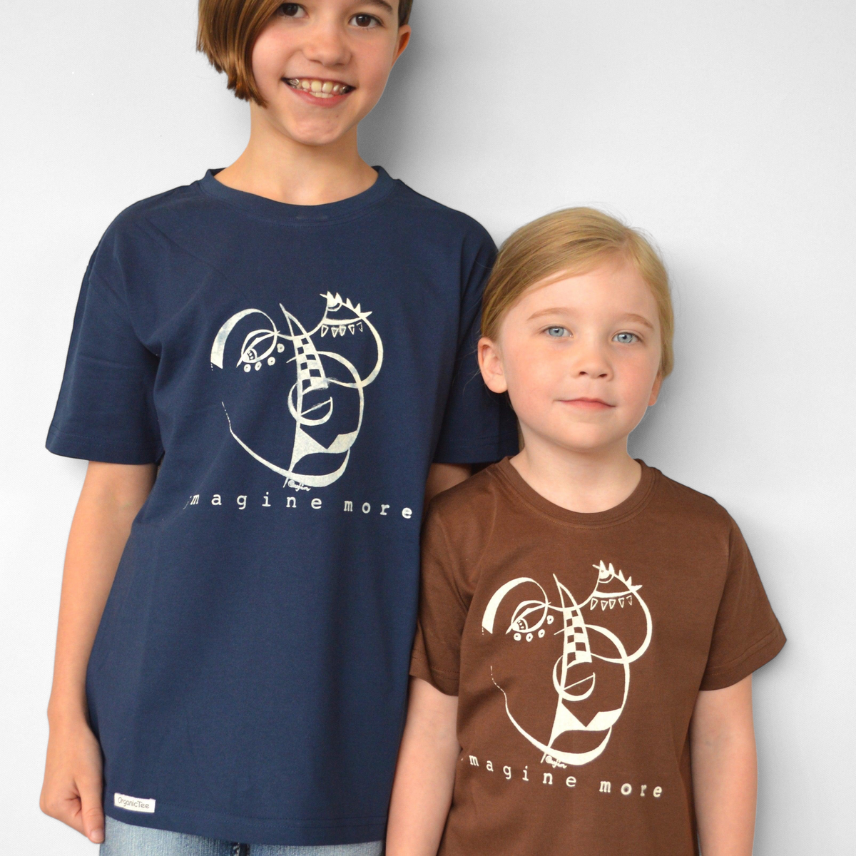 Two children wearing Uni-T organic cotton Imagine More graphic t-shirts in navy blue and brown against a grey wall.