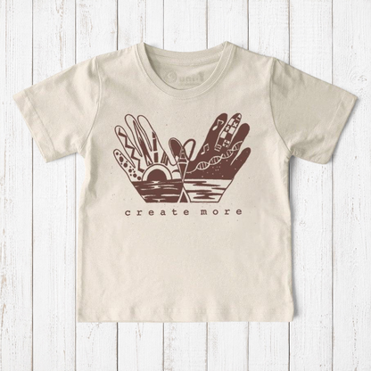 Uni-T organic cotton kids t-shirt in beige with a brown hand-illustrated Create More graphic on a wooden background