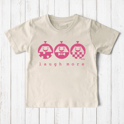 Uni-T kids organic cotton t-shirt in cream with a pink Laugh More graphic featuring three playful illustrated faces.
