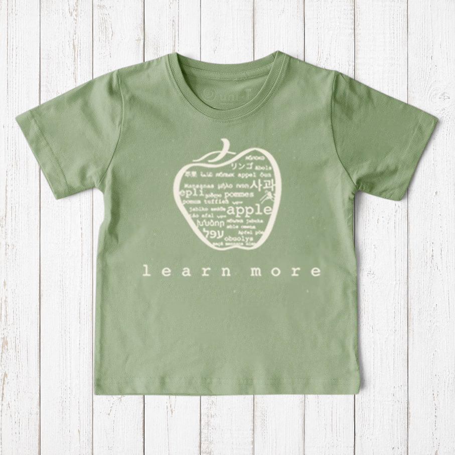 Uni-T kids sage green organic cotton t-shirt featuring a white hand-illustrated apple graphic with multilingual text.