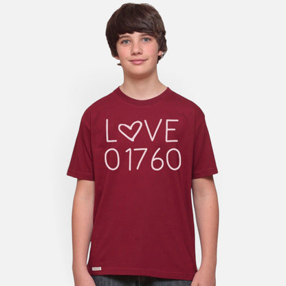 A young boy wearing a maroon Uni-T organic cotton t-shirt with a white Love 01760 graphic print.