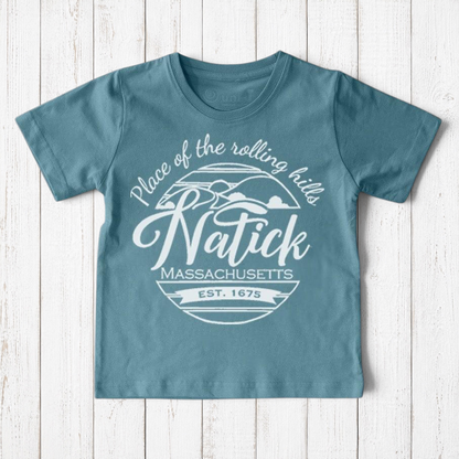 Uni-T kids organic cotton t-shirt in dusty blue with a white Natick Massachusetts circle logo graphic design.