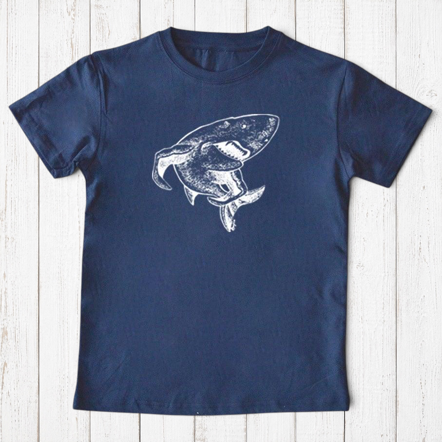 Uni-T kids navy blue organic cotton t-shirt featuring a white hand-illustrated shark graphic from a storybook.