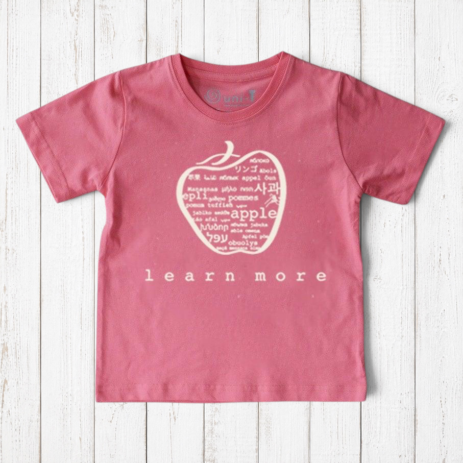 Uni-T kids organic cotton t-shirt in dusty pink featuring a hand-illustrated apple graphic with multilingual text.
