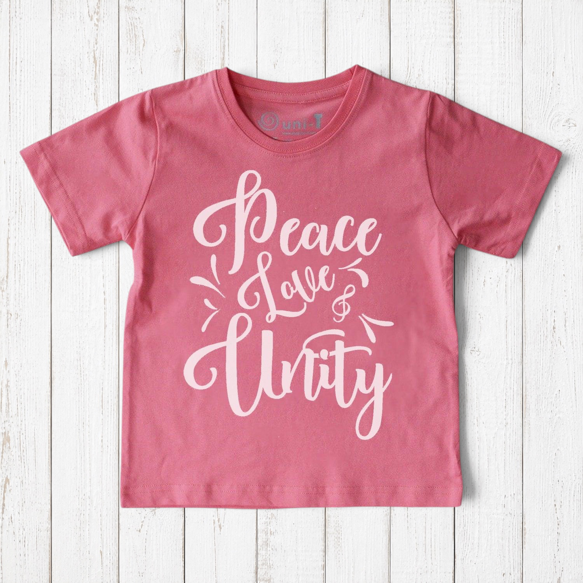 Uni-T kids pink organic cotton t-shirt featuring white hand-drawn Peace Love & Unity typography graphic