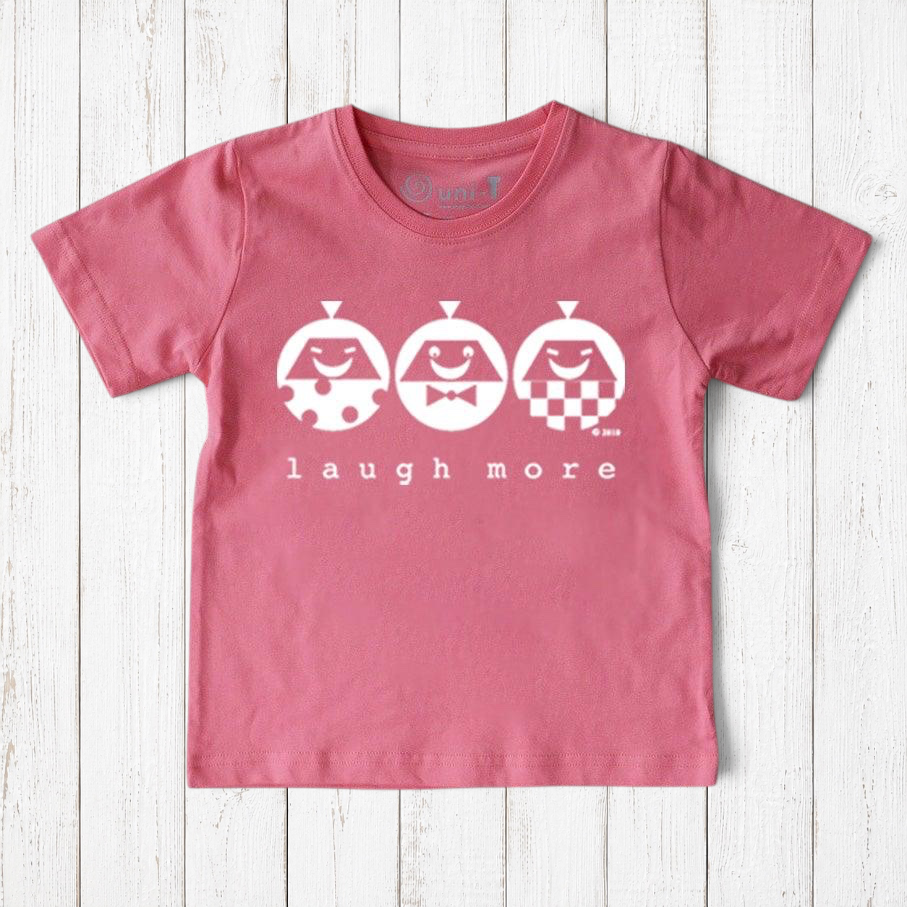 Uni-T organic cotton kids t-shirt in dusty pink with a white Laugh More graphic print on a rustic wood background.