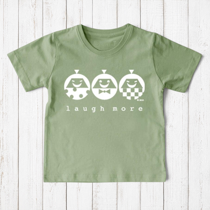Uni-T kids sage green organic cotton t-shirt featuring a white Laugh More graphic with three playful illustrated faces.