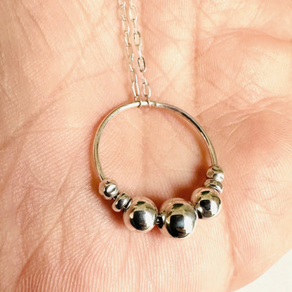 Close-up of Silver Circle Fidget Necklace showing polished sterling beads on a circular pendant. Great as a calming infinity necklace.